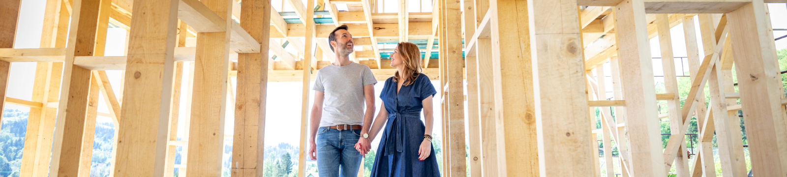 Man and woman holding hands and walking through a home under construction.